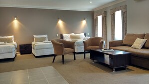 A modern hotel room with two single beds, a sofa, a chair, and a small table. - Seymours on Lydiard (Soldiers Hill)