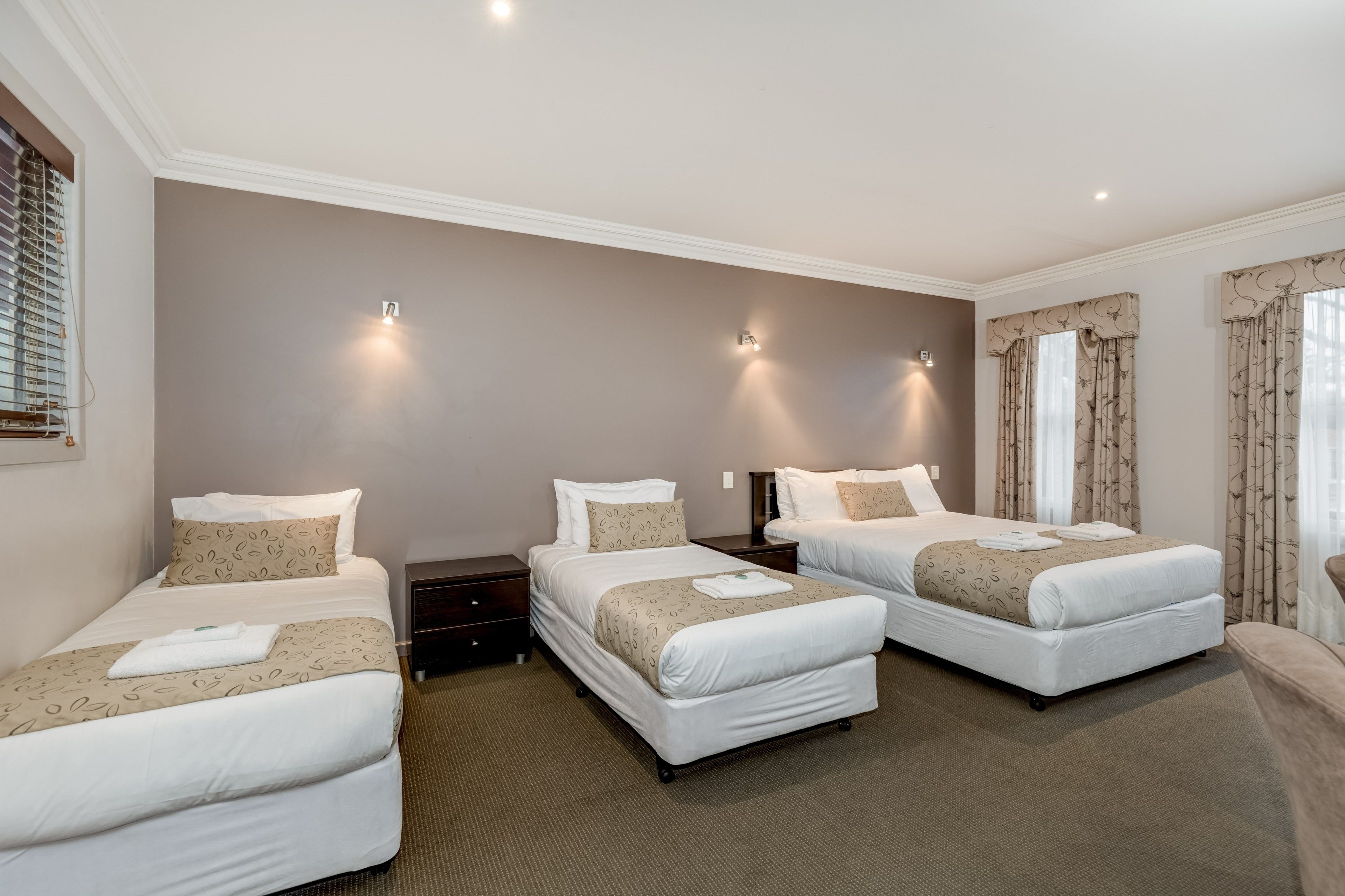 A hotel room with two single beds, a large bed, and a sofa.