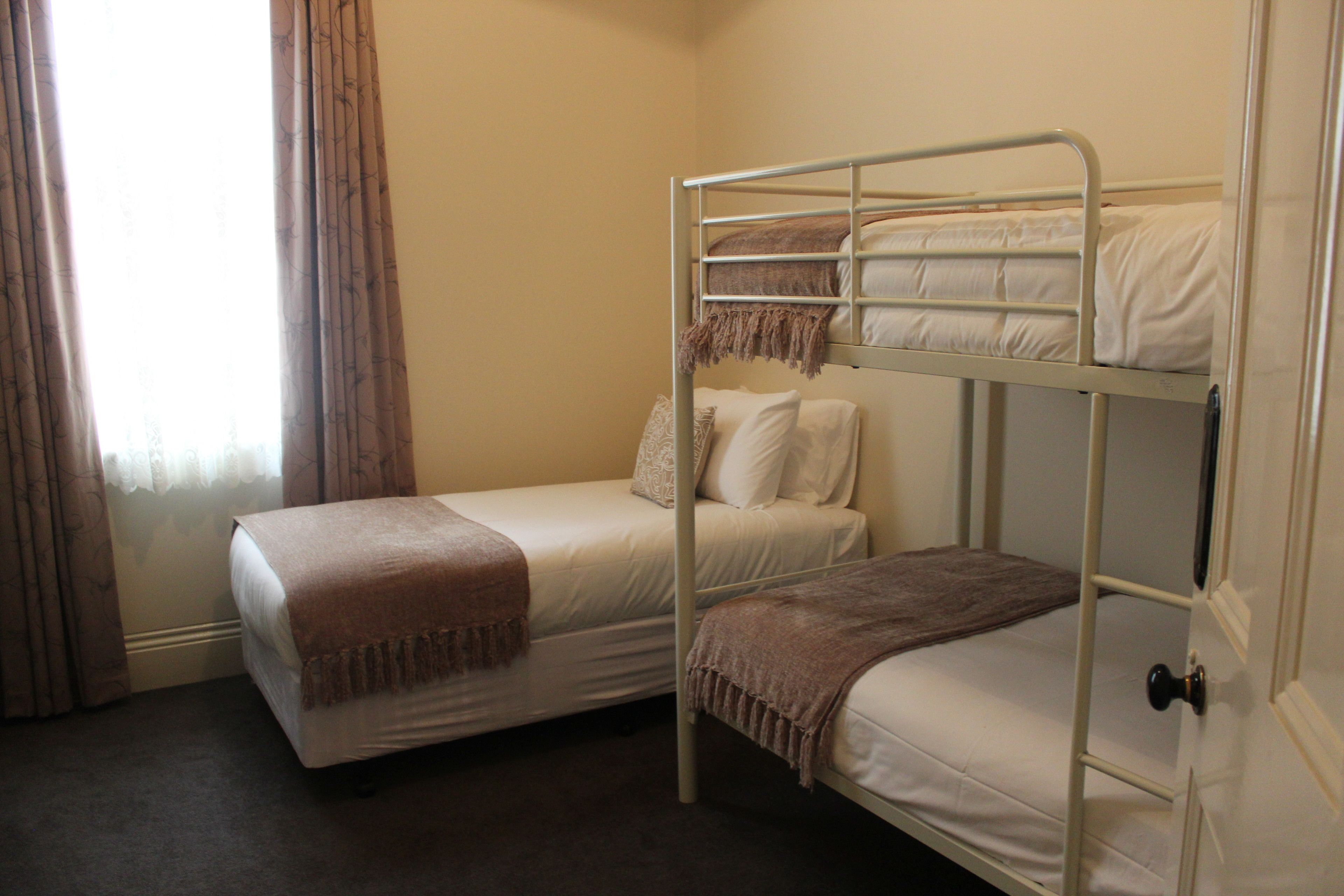 A room with two bunk beds, a window with curtains, and a door.
