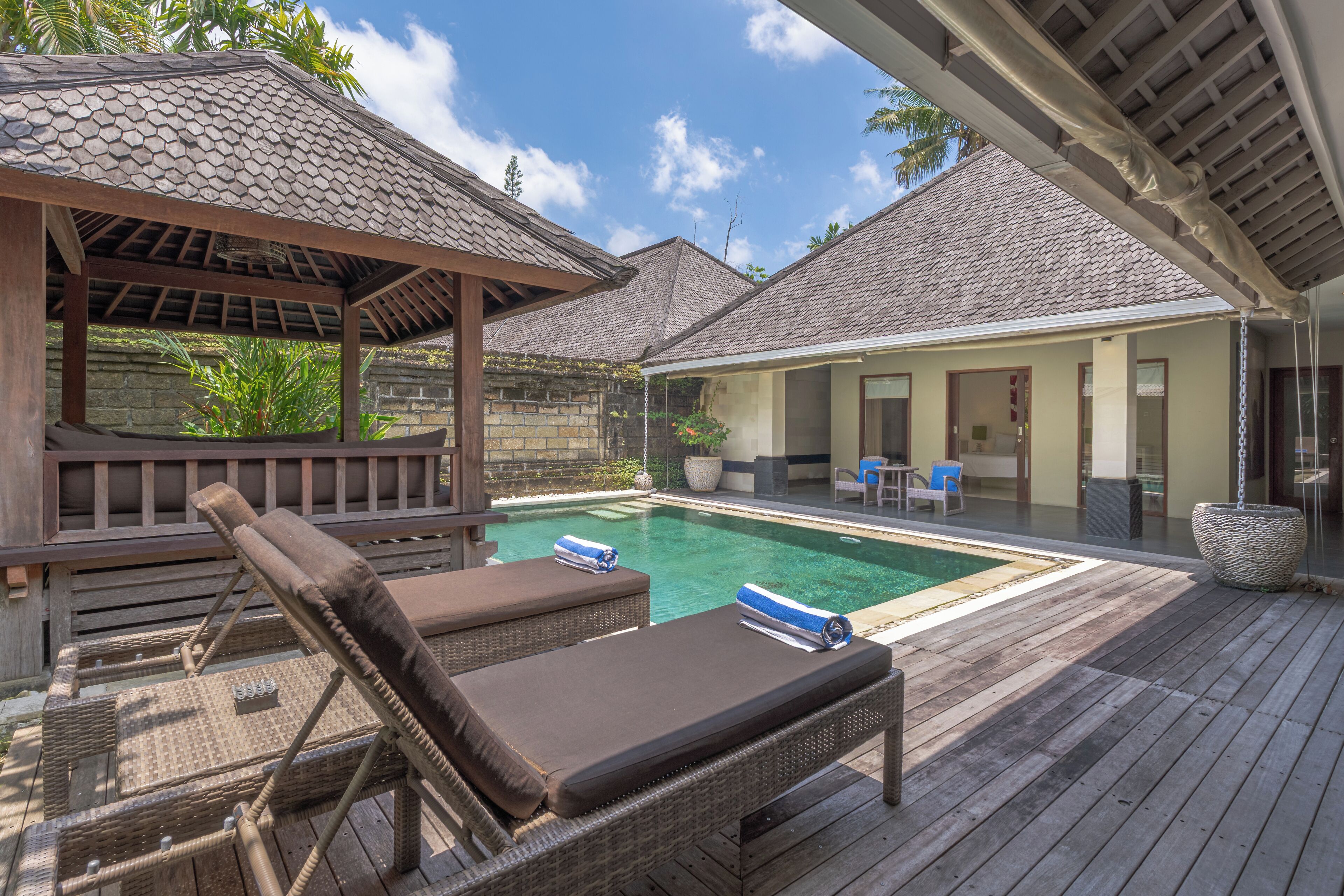 A pool area with lounge chairs and a covered seating area.