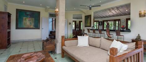 A spacious living area with a large sofa, wooden coffee table, and a dining table.