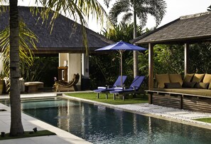 A pool area with lounge chairs, a covered seating area, and palm trees. - Anyar Estate (Kerobokan)