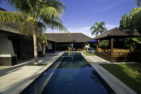 A swimming pool with a wooden deck, palm trees, and a gazebo. - Anyar Estate (Kerobokan)