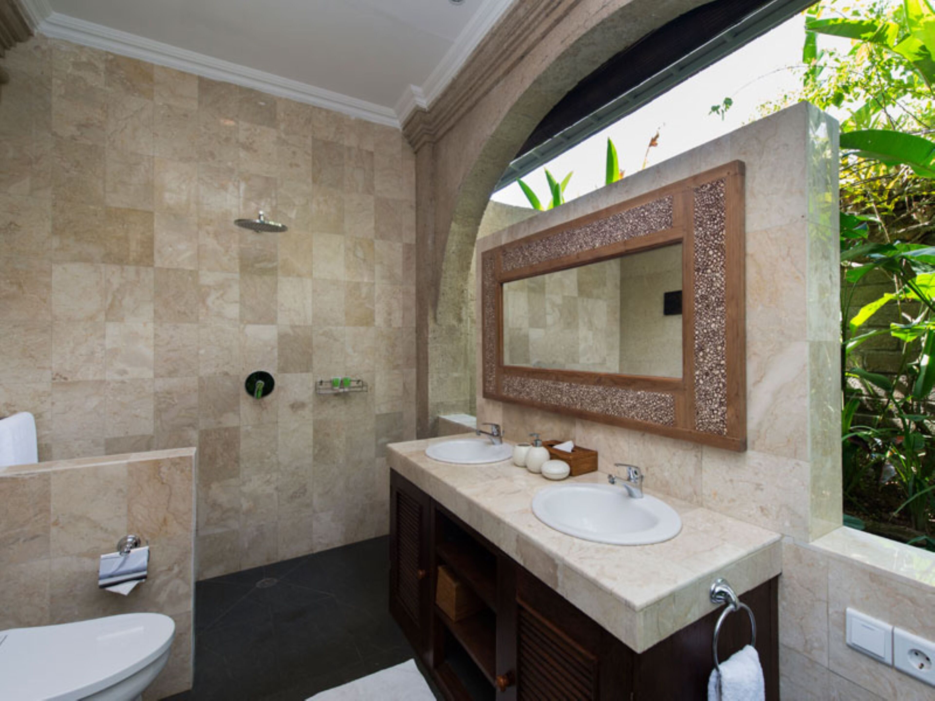 Un baño con dos lavamanos, ducha y un espejo grande con marco decorativo.