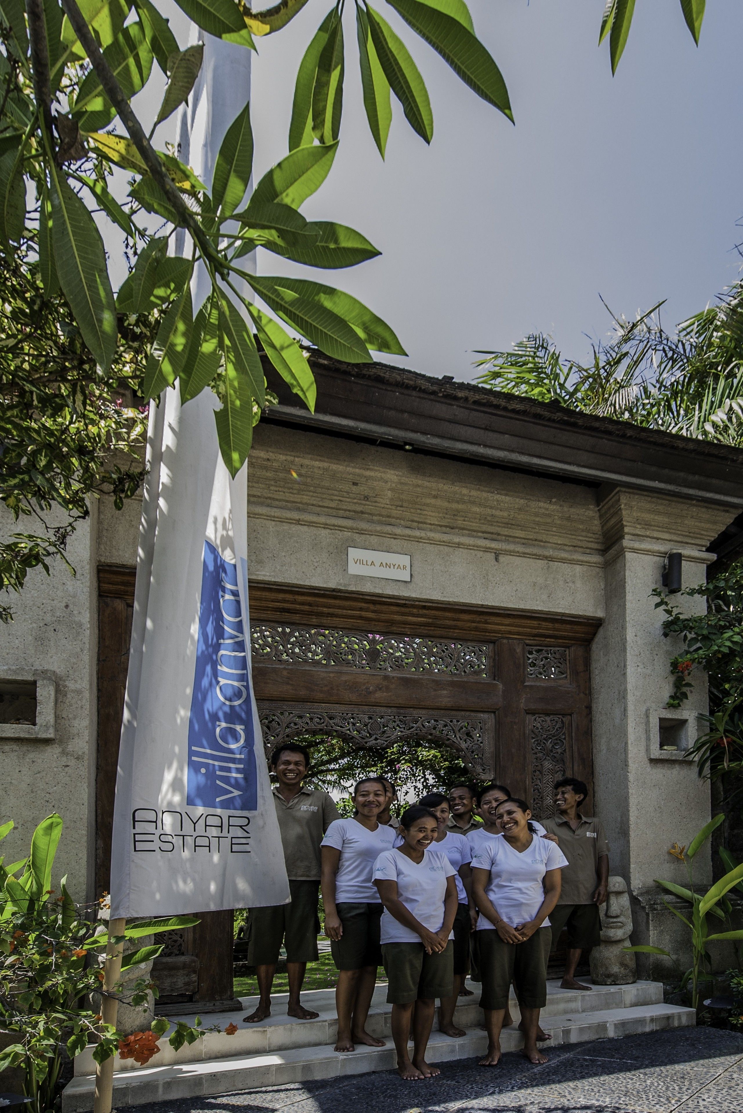 A group of people standing in front of a building with a sign that reads "VILLA ANYAR ESTATE".