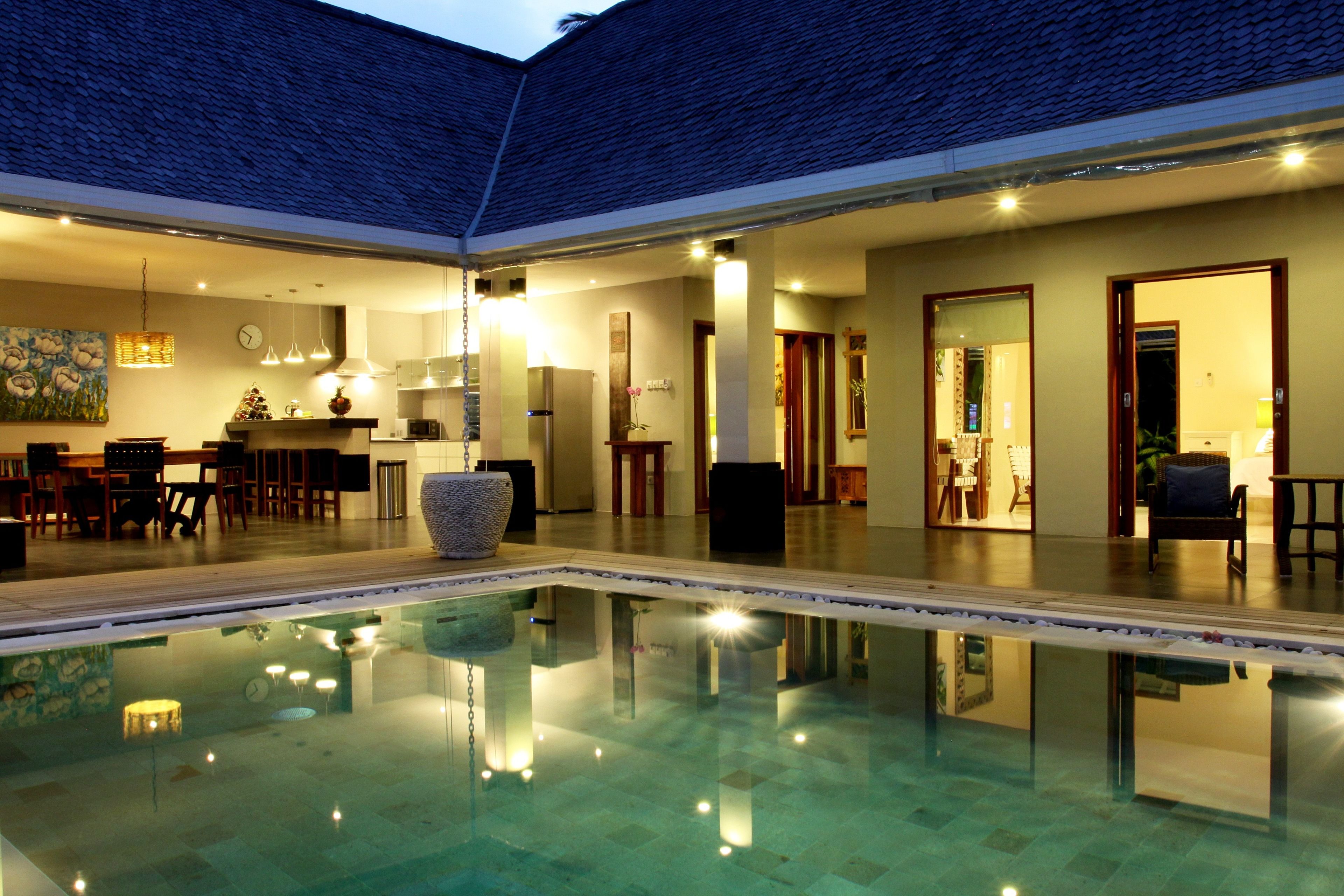 A spacious indoor pool area with a clear view of the surrounding rooms, including a dining area and a kitchen.