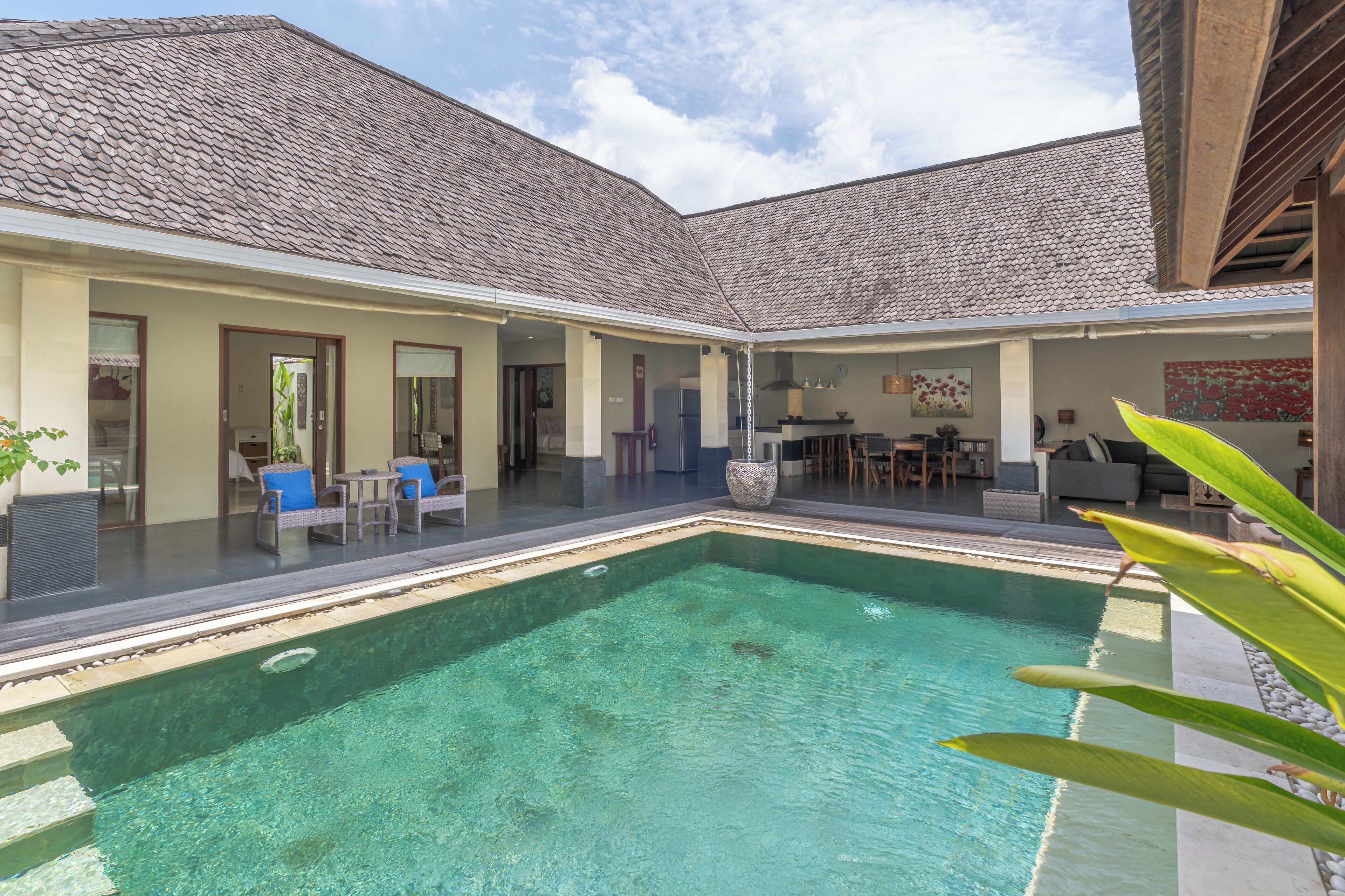 A pool area with a clear blue pool, lounge chairs, and a dining area with outdoor furniture.