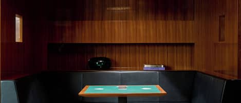 A room with a wooden wall, a black leather bench, and a small table with a blue top.