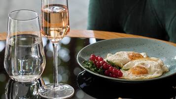A dining table with a plate of food, a glass of water, and a glass of wine.