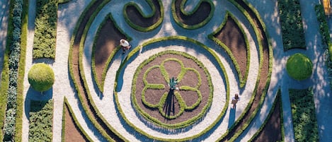 Vista aérea de un jardín meticulosamente cuidado con patrones geométricos y un diseño circular central.