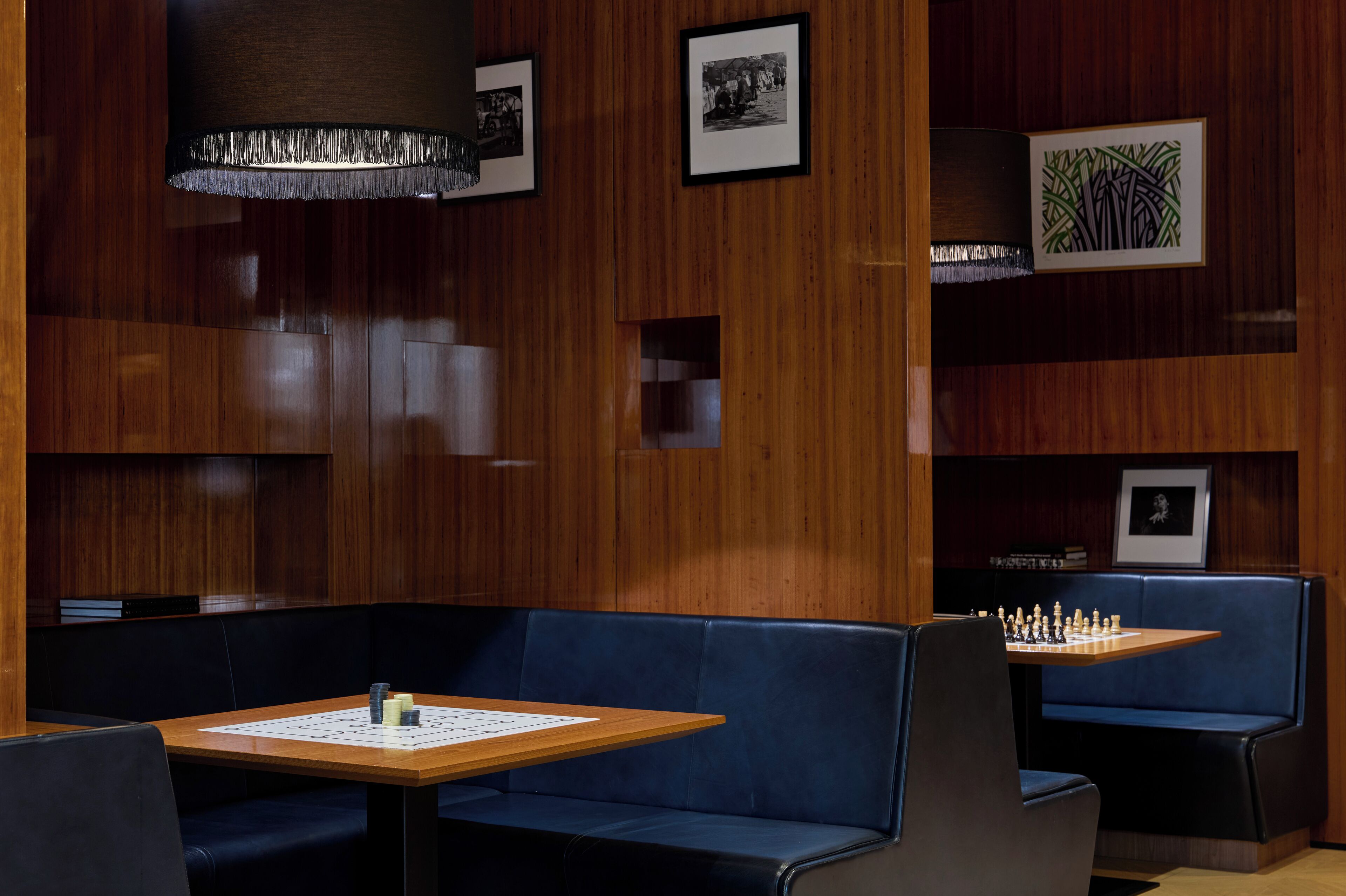 Un espace de détente moderne avec des lambris en bois, des sièges bleus et une table d’échecs.