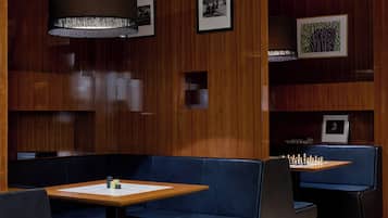 Ein moderner Lounge-Bereich mit Holzvertäfelung, blauen Sitzmöbeln und einem Schachbrett.