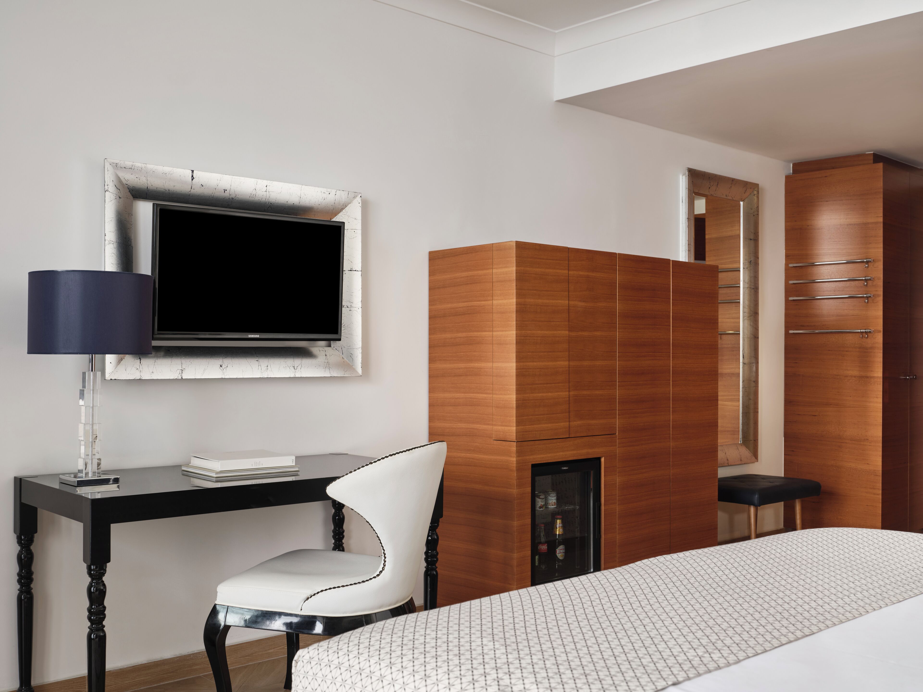 Une chambre d’hôtel moderne avec une armoire en bois, un bureau avec une télévision et un fauteuil confortable.