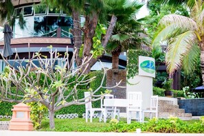 A hotel entrance with a sign, outdoor seating, and lush greenery. - iL Mare Resort (Pranburi)