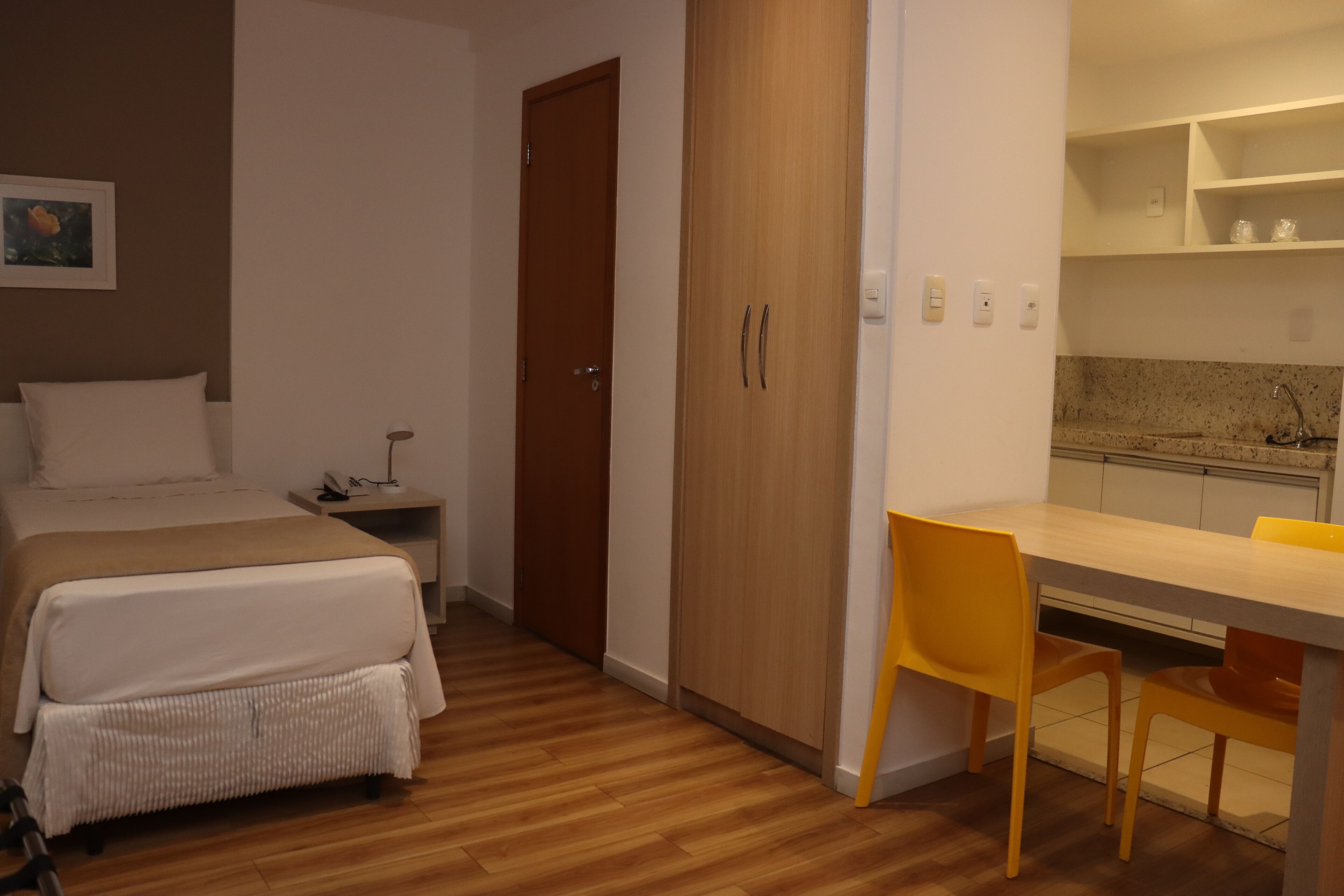 A bedroom with a bed, bedside table, and a wooden wardrobe.