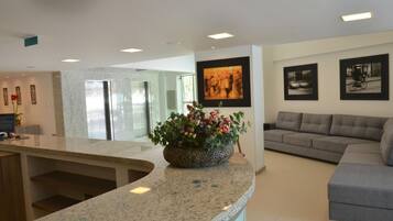A modern kitchen with granite countertops, a central island, and a seating area with a grey sofa.