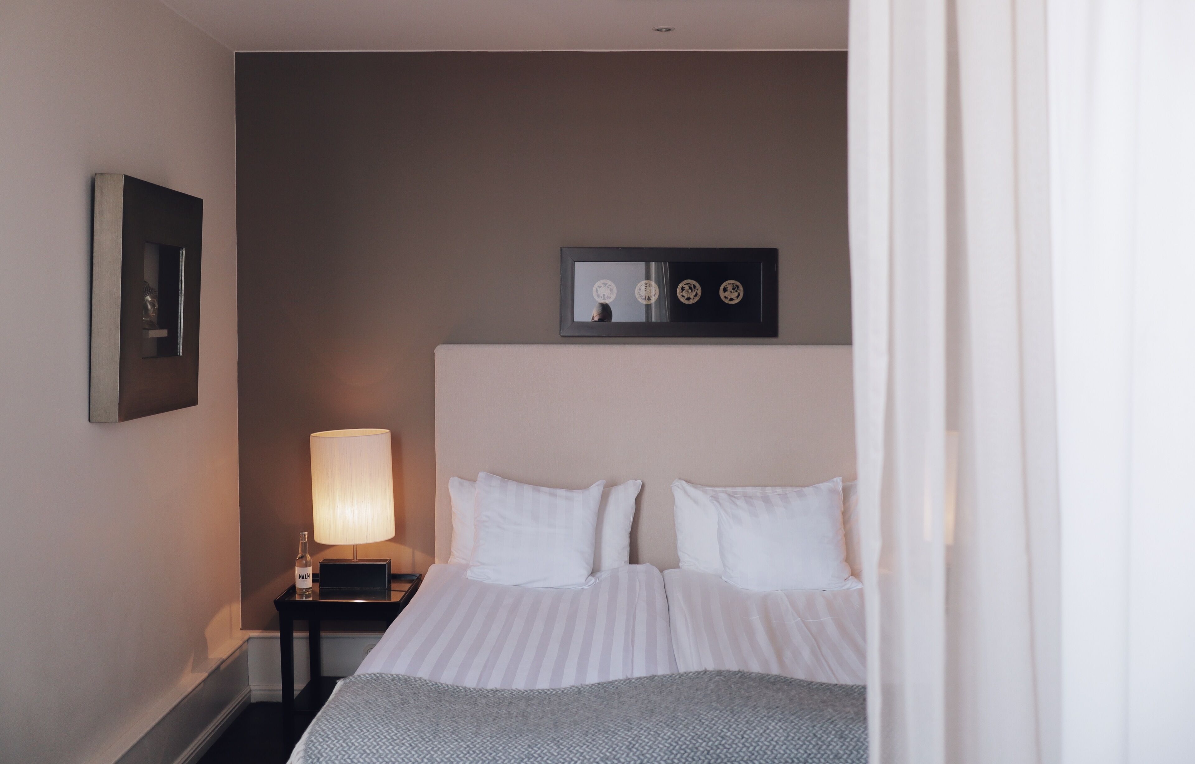 A hotel room with a bed, a nightstand with a lamp, and a framed picture on the wall.