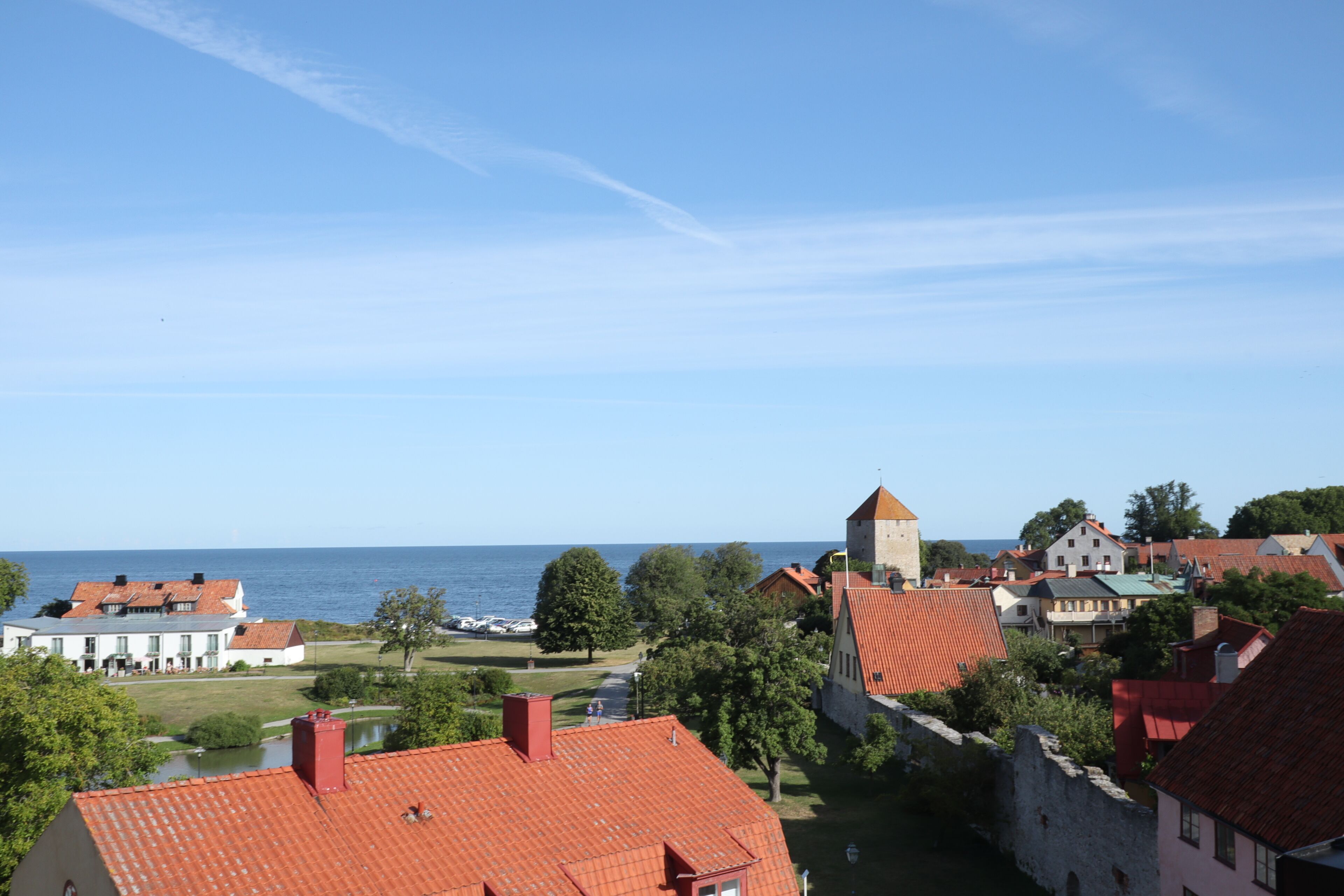 Une ville côtière dotée de bâtiments historiques, d’une tour imposante et offrant une vue sur la mer.