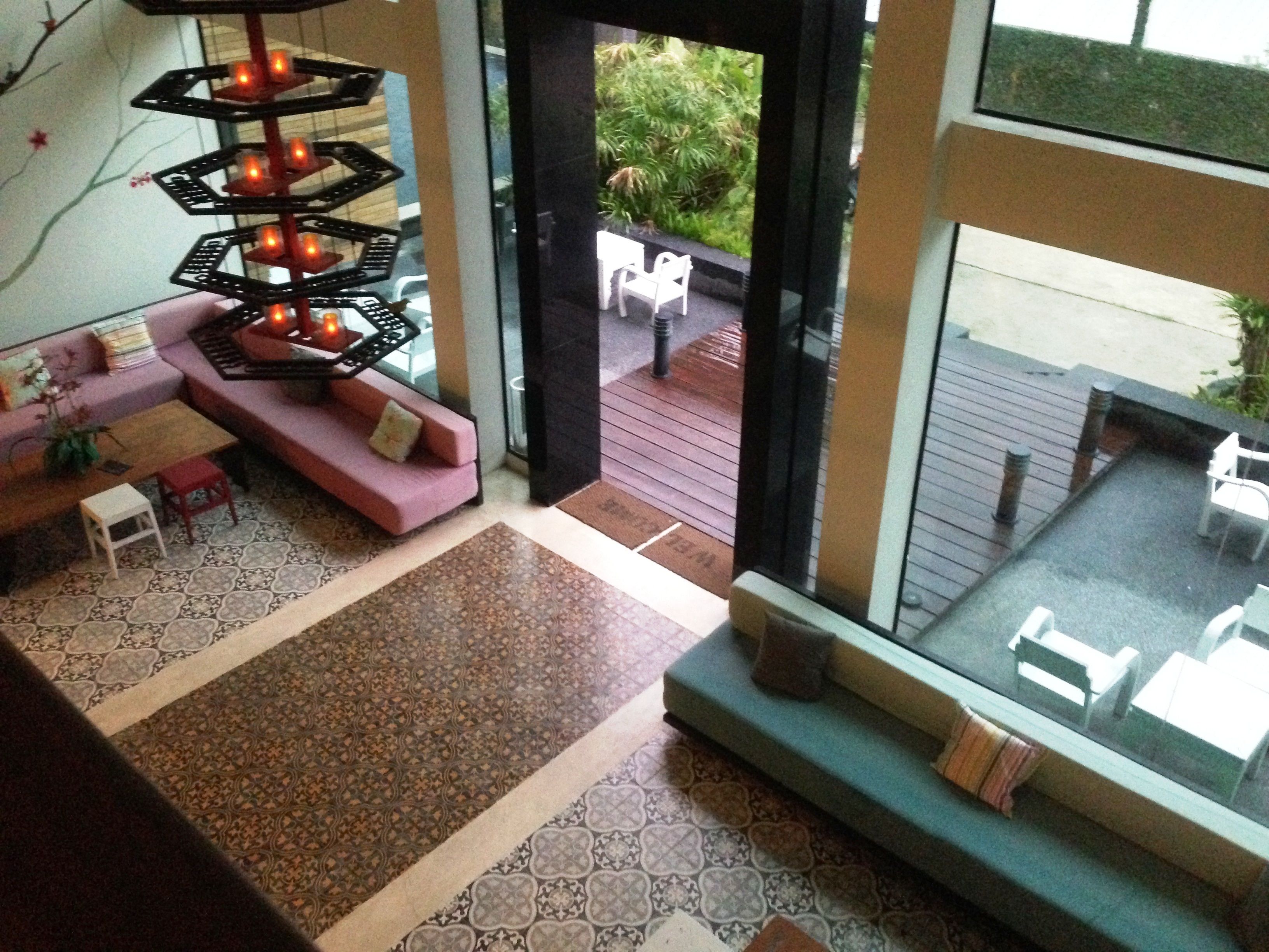 A modern interior with a pink sofa, a patterned rug, and a dining area with a table and chairs.