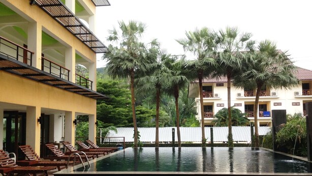 A swimming pool with lounge chairs, surrounded by palm trees and a building with balconies. - Keeree Ele Resort (Ko Chang)