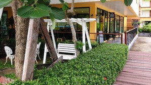 A building with a yellow and white facade, a wooden deck, and a white swing set. - Keeree Ele Resort (Ko Chang)