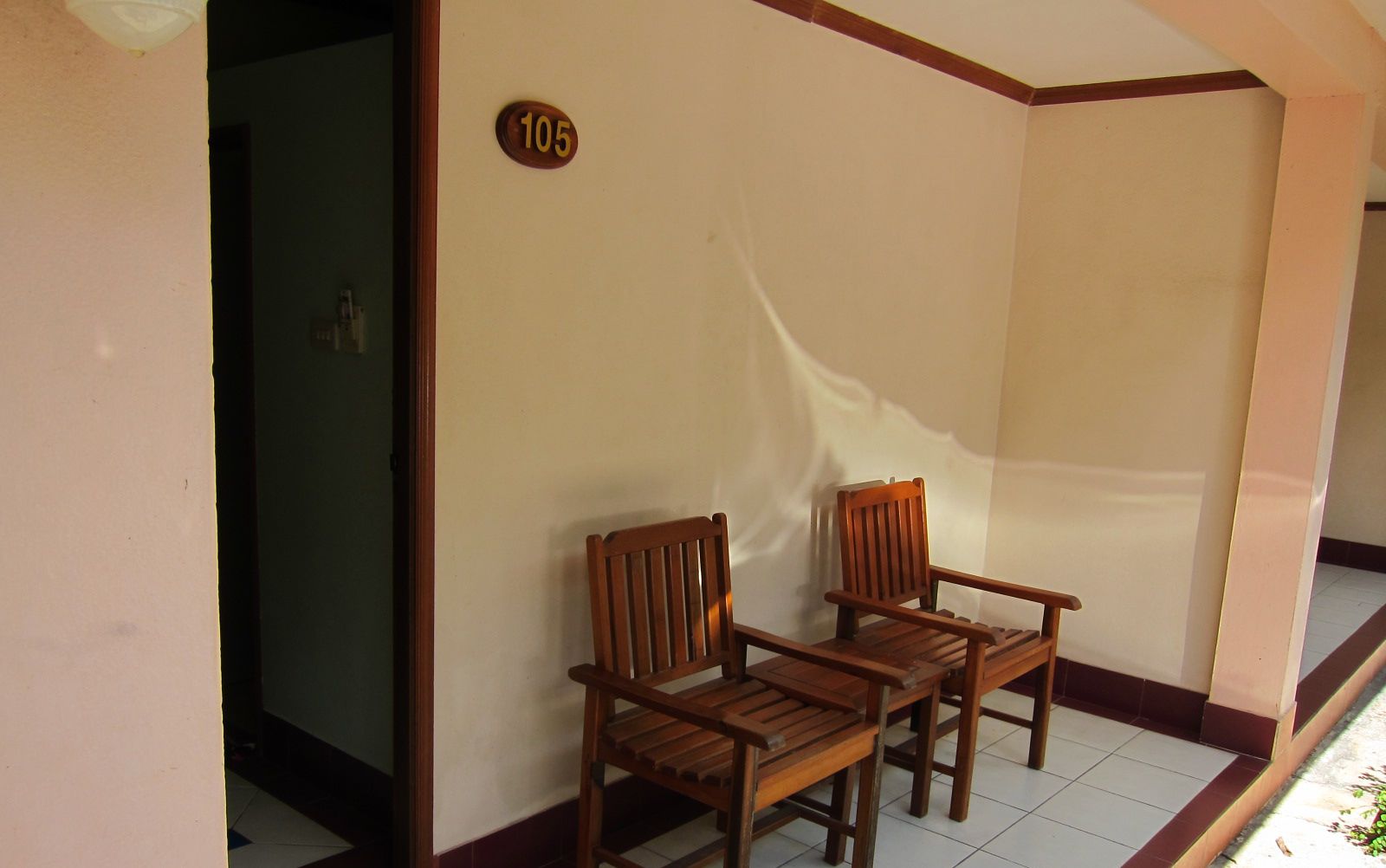A room with two wooden chairs, a number '105' sign, and a tiled floor.