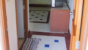A hallway with a tiled floor, a wooden door frame, a small cabinet, and a television on a stand. - Oasis Resort (Krabi)