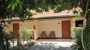 A building with a red-tiled roof, two wooden doors, and a small porch with two wooden chairs. - Oasis Resort (Krabi)