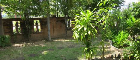 A garden with a variety of plants and a brick wall with statues.