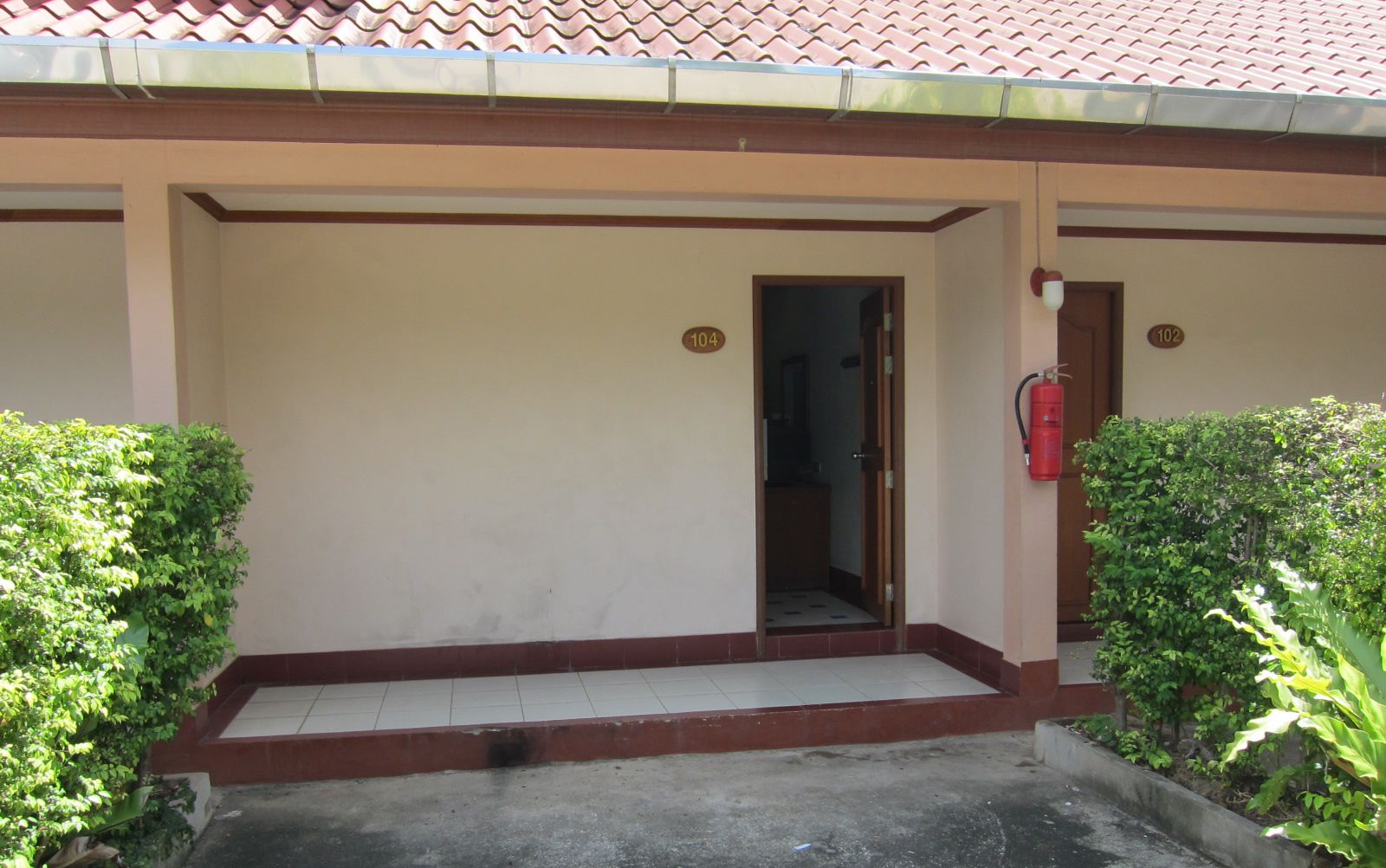A building entrance with a tiled floor, a door, and a fire extinguisher mounted on the wall.