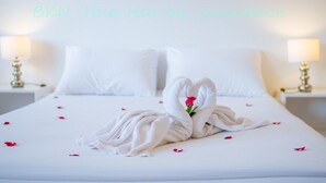 Una camera d'albergo con un letto, biancheria da letto bianca, due comodini con lampade e una parete con scritte.