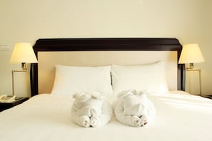 A hotel room with a neatly made bed, two pillows, two bedside lamps, and a telephone on the nightstand. - LK Crystal Place (Pattaya)