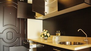 A modern kitchen with dark cabinetry, a stainless steel sink, and a vase with flowers. - LK Crystal Place (Pattaya)