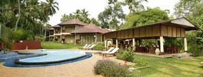 A resort with a swimming pool, lounge chairs, and a covered outdoor area.