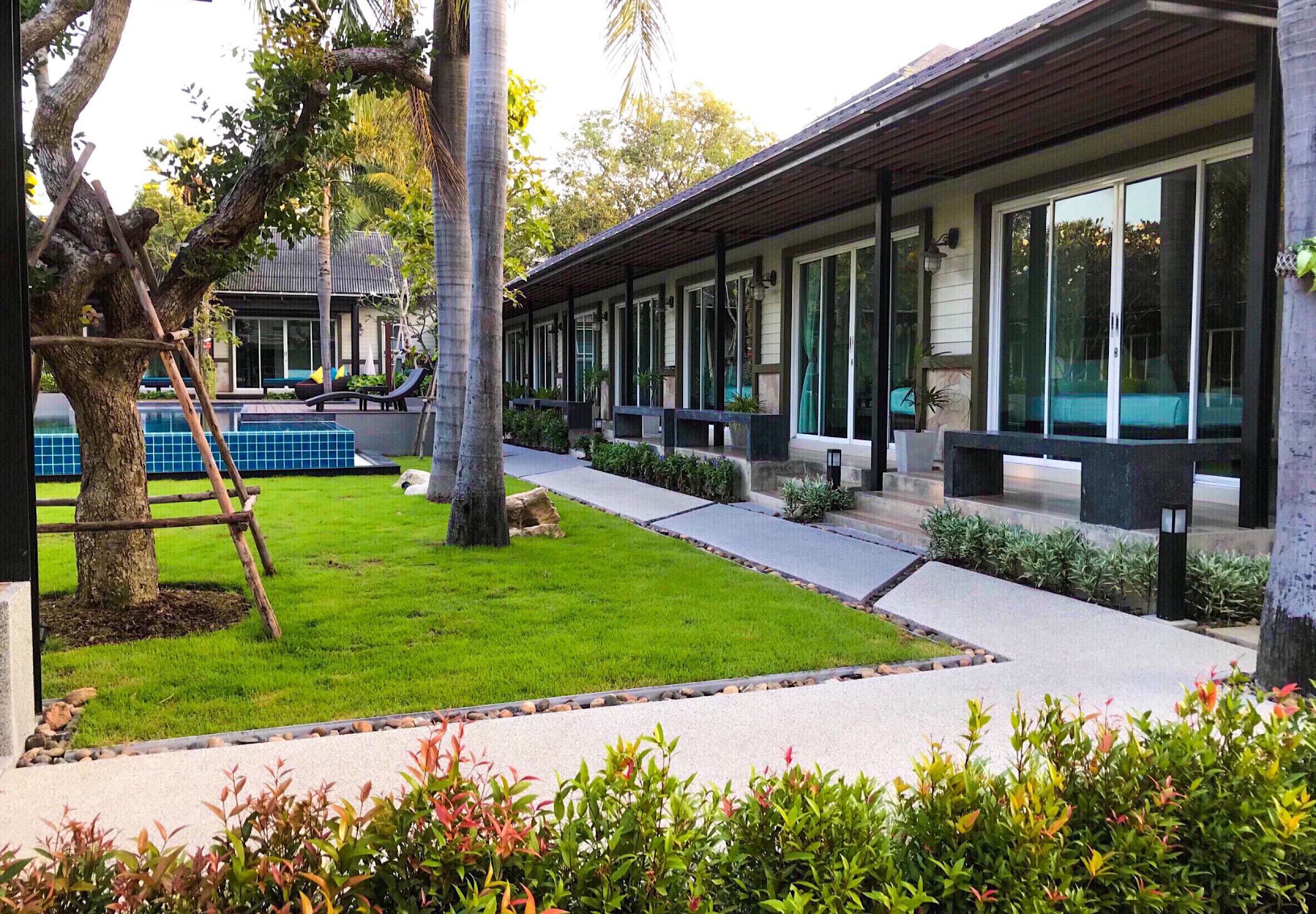 Ein modernes Hotel mit Pool, Sitzgelegenheiten im Freien und einem gepflegten Garten.