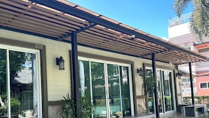 A modern building with a covered patio area, large windows, and outdoor seating. - Nirundorn Resort (Cha-am)