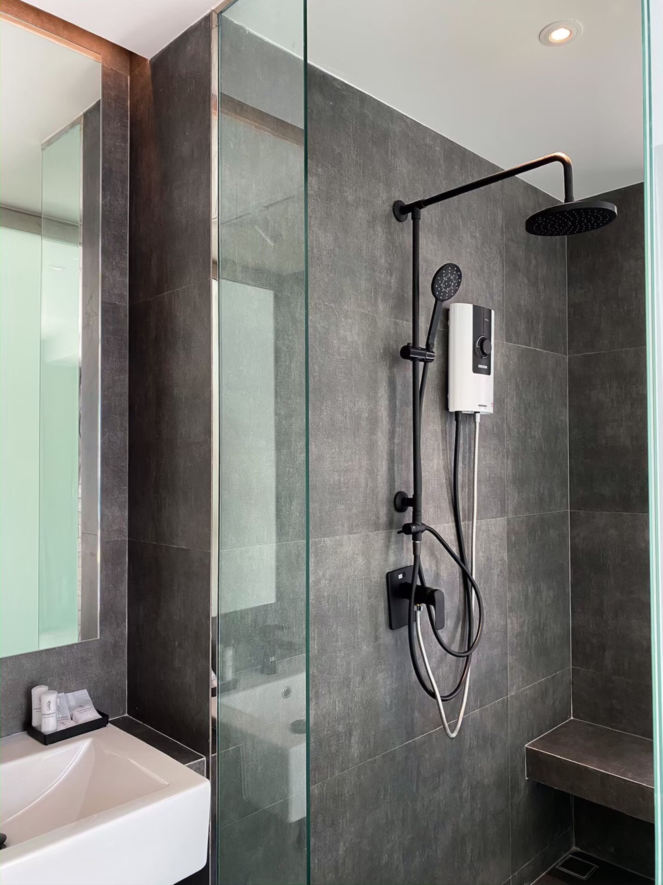 Un baño moderno con cabina de ducha de vidrio, lavamanos empotrado y ducha de mano.