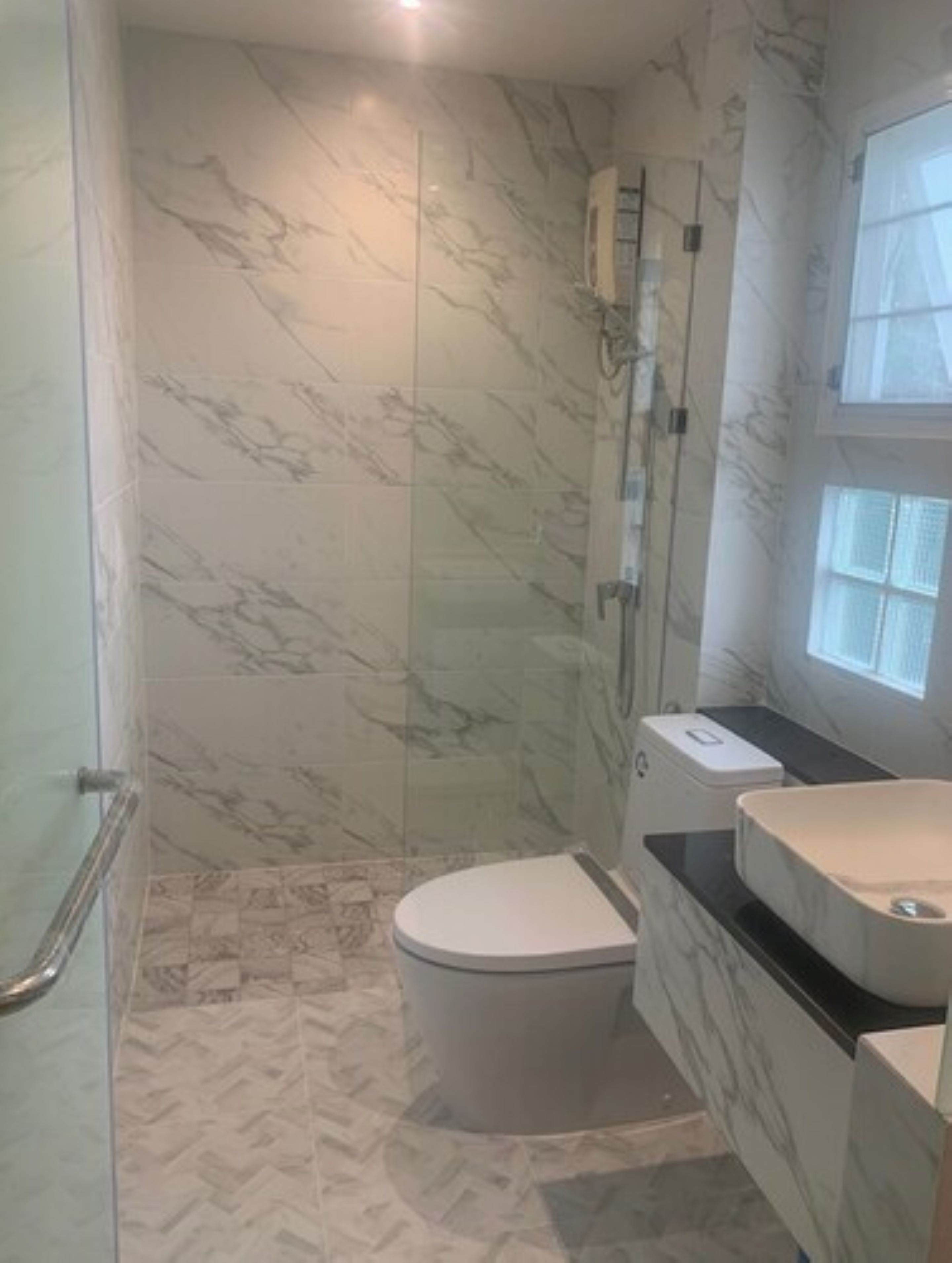 A bathroom with a toilet, a shower, and a sink.