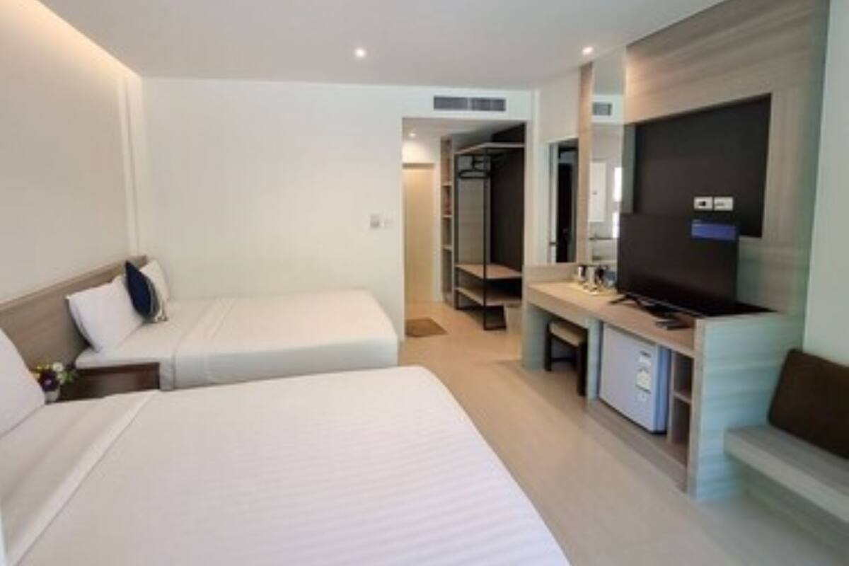 A hotel room with two beds, a TV, a desk, and a wardrobe.
