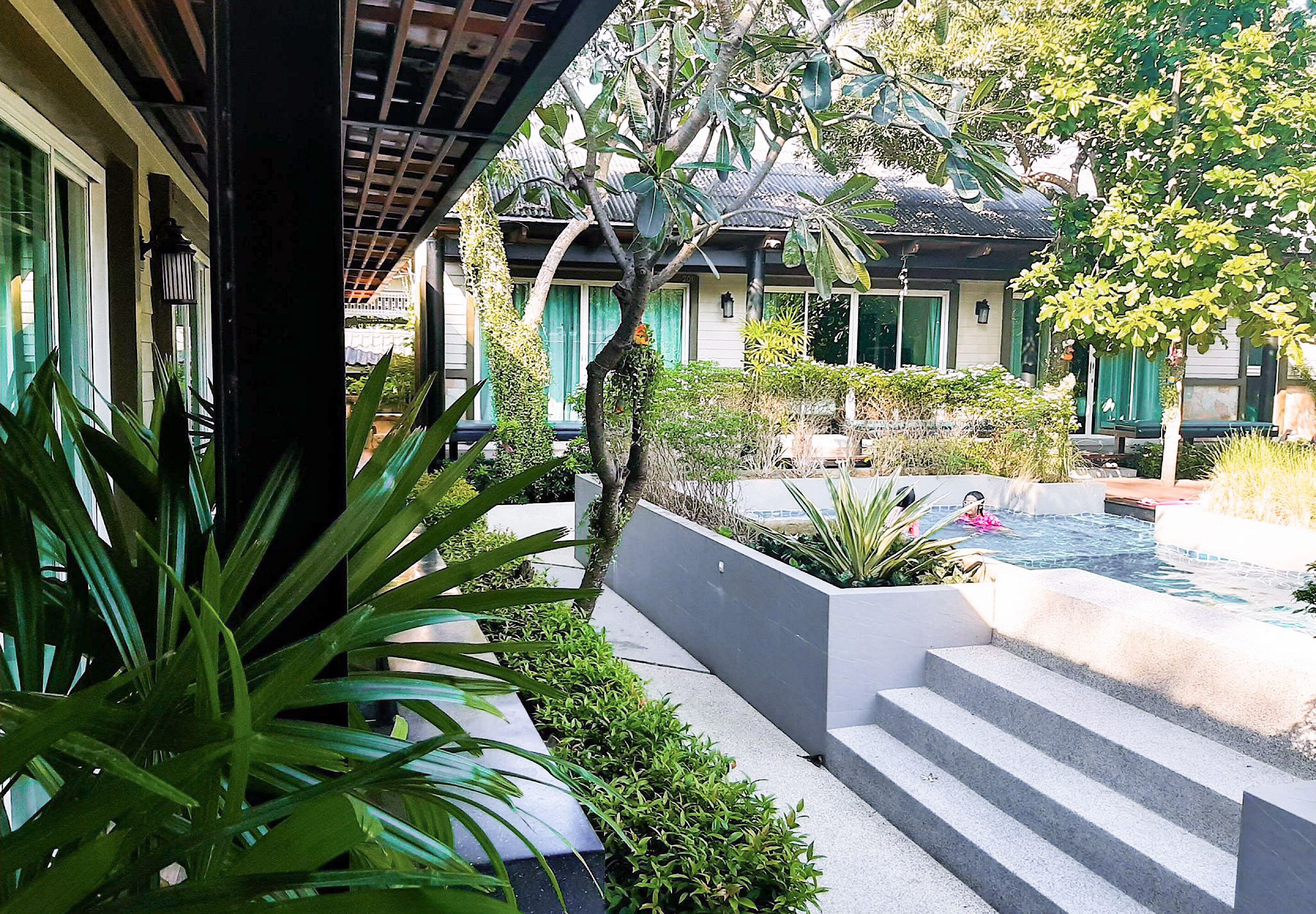 A courtyard with a swimming pool, steps leading to a poolside area, and lush greenery.