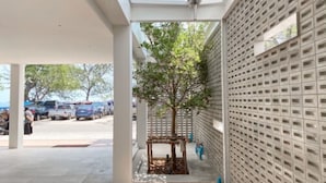 An outdoor area with a covered walkway, a tree, and a wall with a grid pattern. - Nirundorn Resort (Cha-am)