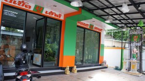 Un edificio con facciata verde e arancione, ampie finestre in vetro e una motocicletta parcheggiata davanti.