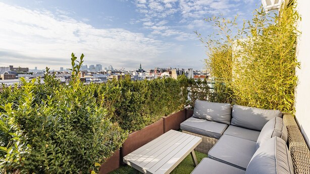 A rooftop terrace with a sofa set, a table, and a view of the city skyline. - Résidence Courcelle (Levallois-Perret)