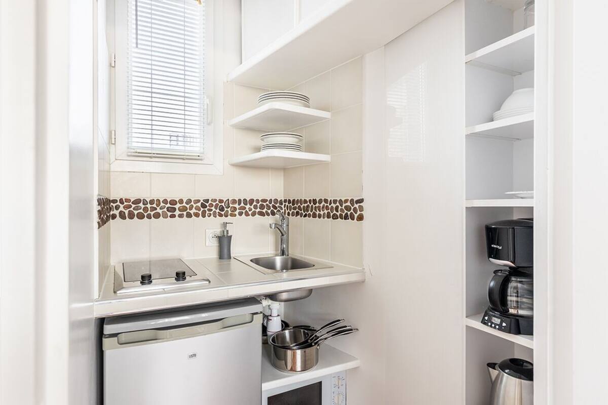Una cocina compacta con estufa integrada, lavamanos y estanterías.