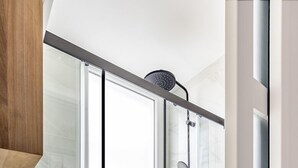 A modern bathroom with a glass shower enclosure, a marble sink, and patterned floor tiles. - Résidence Courcelle (Levallois-Perret)