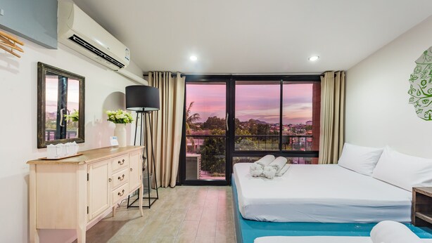 Una habitación de hotel con un ventanal grande, una cama, un escritorio y un aparador.