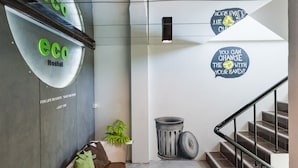 Interior moderno de un hostal con un banco, bolsas verdes y pegatinas motivacionales en la pared.