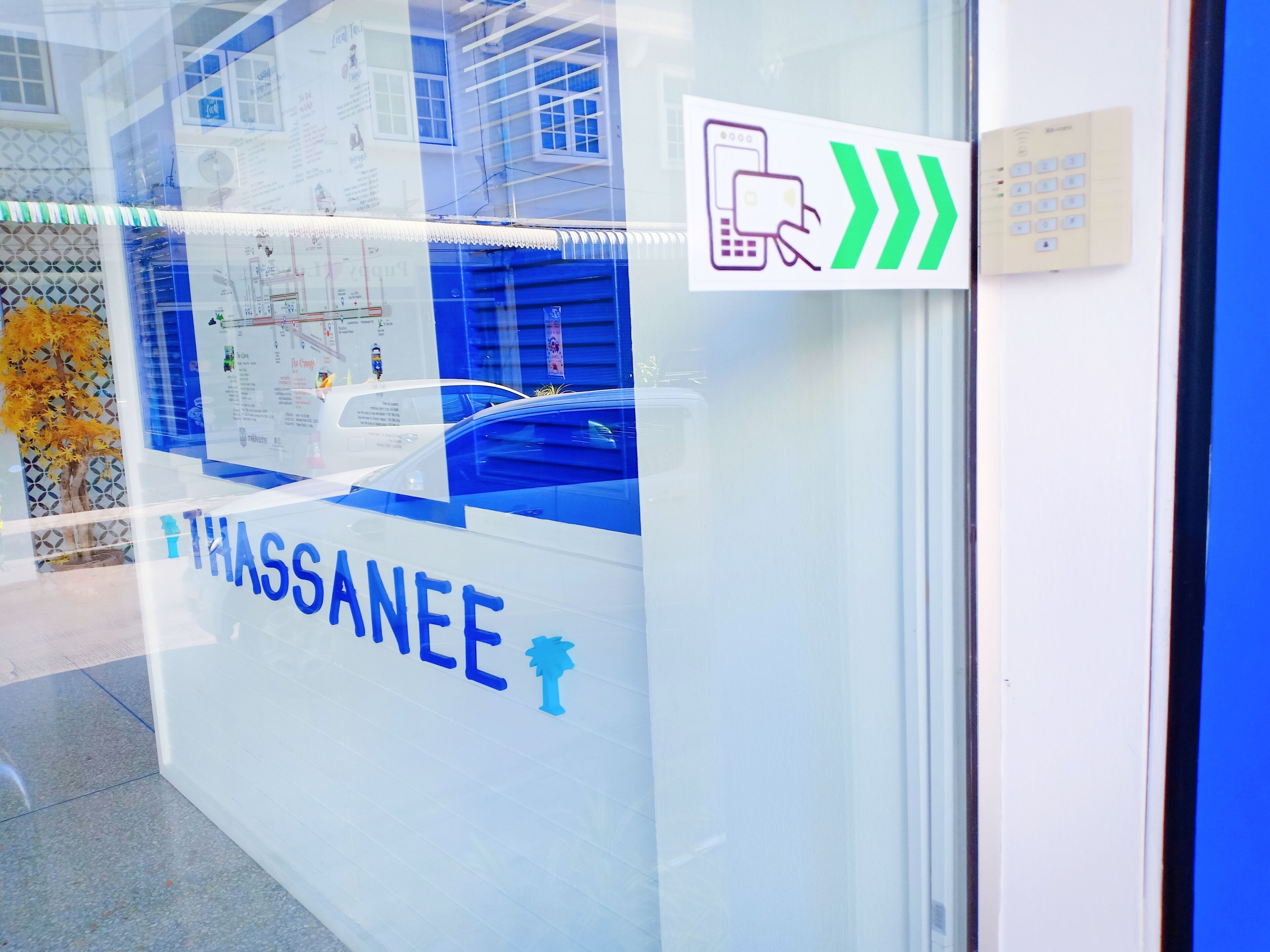 A glass door with the name "THASSANEE" and a palm tree logo.