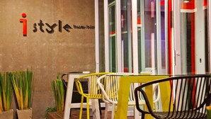 A modern interior with a concrete wall, a glass door, and a yellow table with white chairs. - I Style Hua Hin Hotel (Hua Hin)