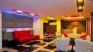 A hotel lobby with a checkered floor, a red sofa, and a white sofa with red cushions. - I Style Hua Hin Hotel (Hua Hin)